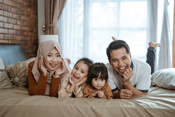 Ayah, ibu dan dua anak perempuan tertawa bahagia saat berbaring di tempat tidur — Stok Foto