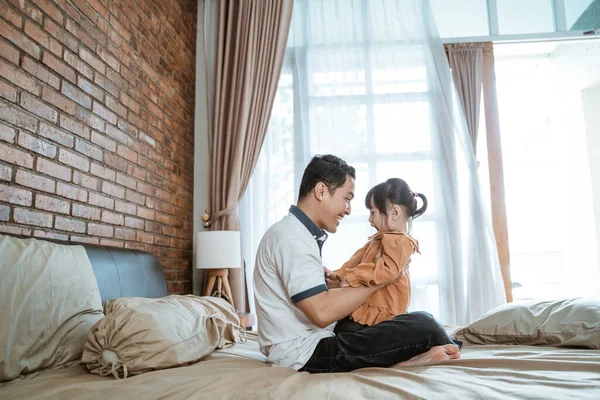 Ayah bermain dengan putri kecilnya sambil duduk di tempat tidur — Stok Foto