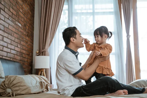 Батько сміявся щасливо, коли його ніс торкнулася маленька дівчинка — стокове фото