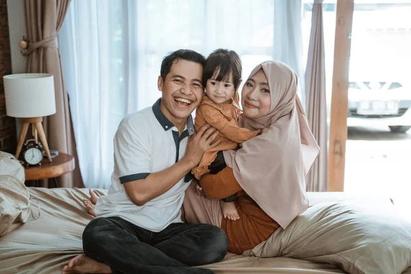 Keluarga Muslim tersenyum bahagia ketika memeluk sambil duduk di tempat tidur — Stok Foto