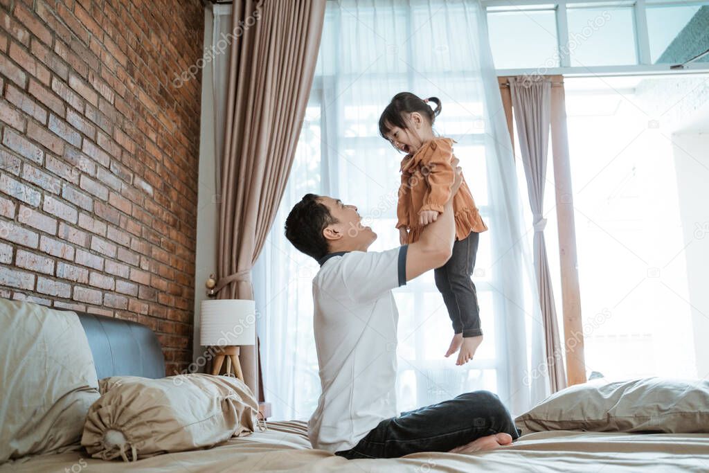 little girl laughed happily when she was lifted up by her father
