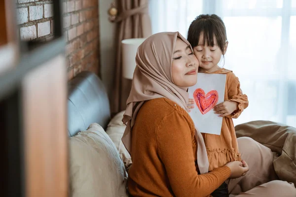 Verschleierte Mutter und das kleine Mädchen schließen beim Umarmen die Augen — Stockfoto