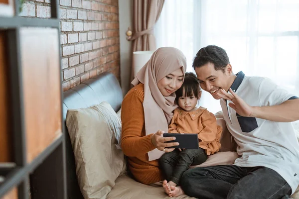 Ασιατική μουσουλμανική οικογένεια μαζί βλέποντας μια οθόνη του τηλεφώνου κατά την κλήση βίντεο — Φωτογραφία Αρχείου