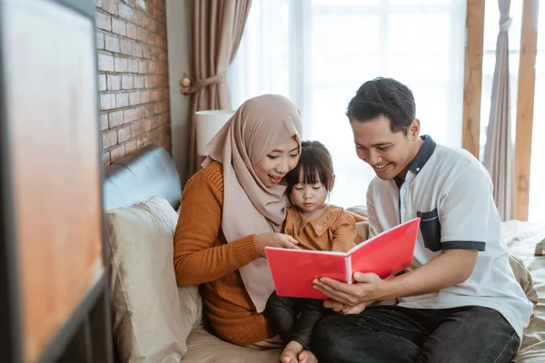 Ensemble d'une petite fille avec ses parents lors de la lecture d'un livre — Photo