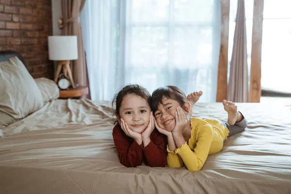Šťastné dvě malé holčičky ležící na posteli — Stock fotografie