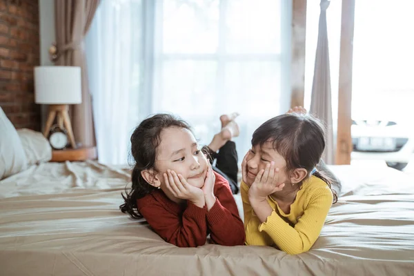 Bahagia dua gadis kecil berbaring di tempat tidur — Stok Foto