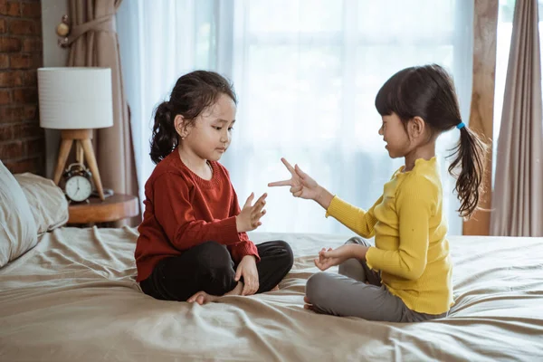 Две маленькие азиатские девочки радостно улыбались, играя ножницами из бумаги. — стоковое фото