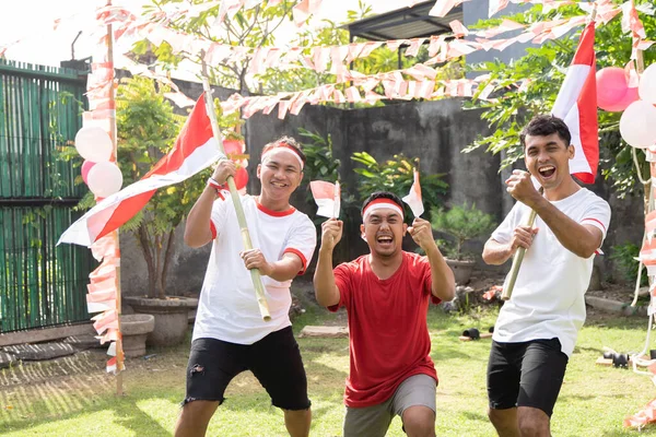 Tiga anak laki-laki Asia menyemangati tangan mereka sambil membawa bendera Indonesia — Stok Foto