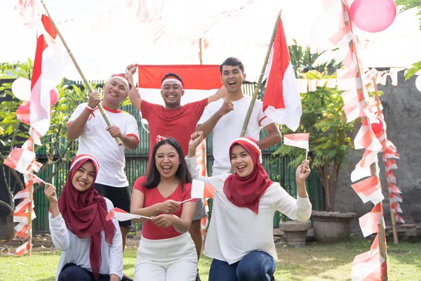 Tiga gadis berjongkok di depan dan tiga anak laki-laki berdiri di belakang membawa bendera Indonesia — Stok Foto