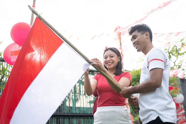Gadis muda memasang bendera dan pemuda memegang tongkat bambu — Stok Foto