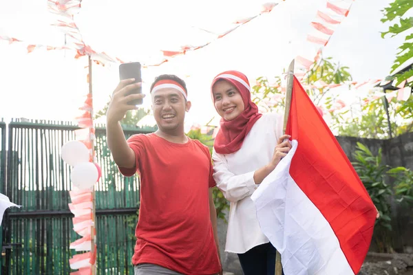 Joven pareja tomar selfies con cámaras mientras lleva rojo y blanco atributos —  Fotos de Stock