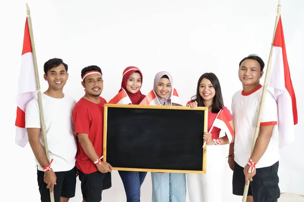 Amigos indonesios sosteniendo una bandera y pizarra negra —  Fotos de Stock