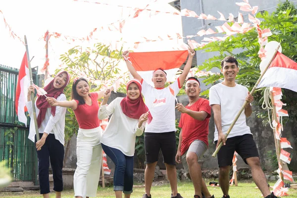 Asiatiska pojkar och flickor ler medan de bär och för den indonesiska flaggan — Stockfoto