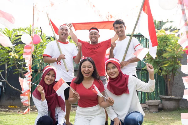 Drei Mädchen hocken davor und drei Jungen stehen dahinter und tragen indonesische Flaggen — Stockfoto
