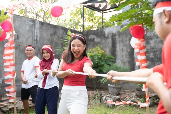 Tiga orang dalam satu tim mencoba menarik tali dengan keras selama kompetisi tarik-menarik — Stok Foto