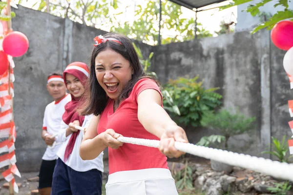 Perempuan muda Asia berteriak dengan antusias ketika menarik tali selama tarik-menarik permainan perang — Stok Foto