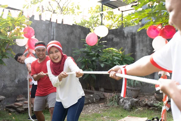 Tiga orang dalam satu tim mencoba menarik tali dengan keras selama kompetisi tarik-menarik — Stok Foto