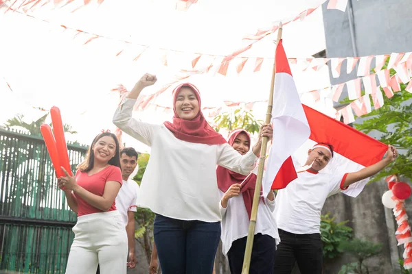 Das verschleierte asiatische Mädchen steht mit geballten Fäusten und einem Bambusstock unter indonesischer Flagge — Stockfoto