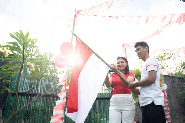 Gadis dan pria muda yang ceria saling membantu satu sama lain memasang bendera di bambu — Stok Foto