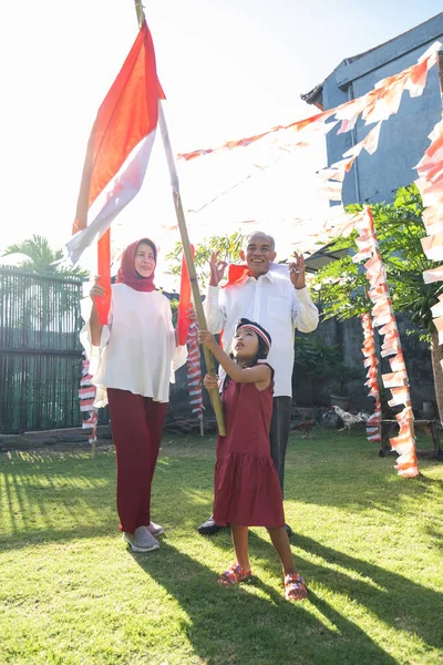 Gadis kecil memegang bendera Indonesia sementara dengan kakek-neneknya — Stok Foto