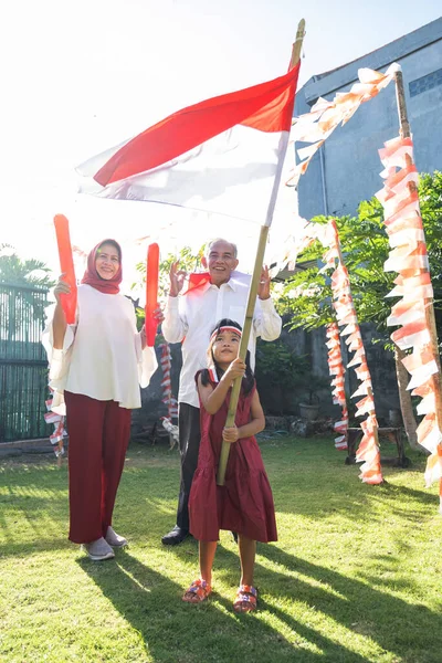 Gadis kecil Asia mengibarkan bendera Indonesia dengan tongkat bersama kakek-neneknya — Stok Foto