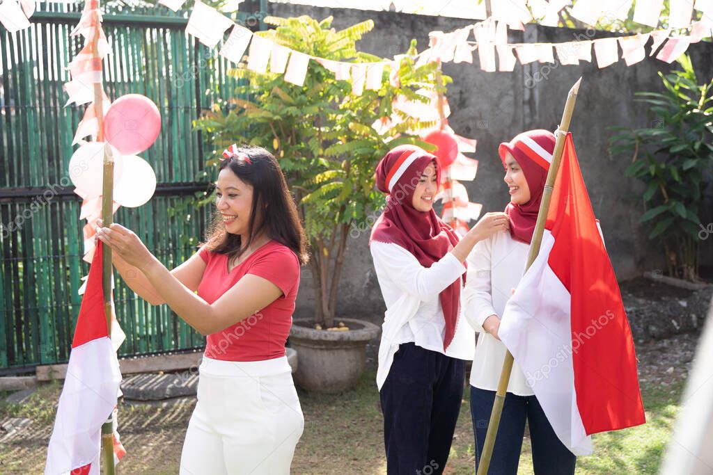 three Asian women smiled while putting up Indonesian flags and headbands