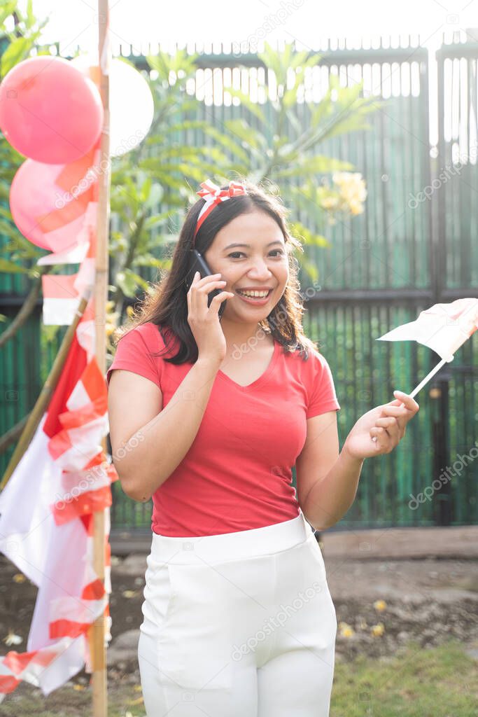 Asian girls smile happily while on the phone wearing red and white attributes