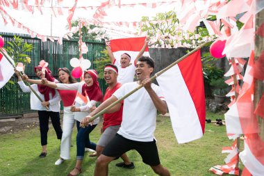 Bir grup arkadaş özellikler takar ve tarlada kırmızı ve beyaz bayraklar taşır