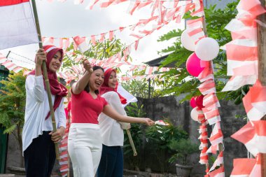 Bir grup neşeli kız ellerinde kırmızı ve beyaz bayraklar taşıyorlar.