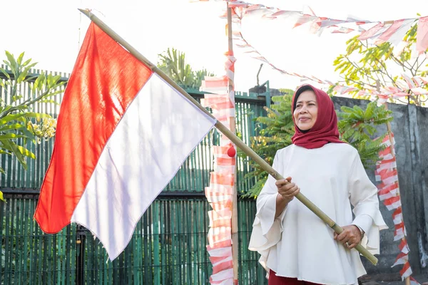 Hooded oude vrouw met een Indonesisch gemarkeerde bamboe stok — Stockfoto