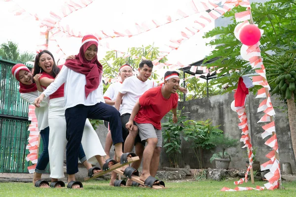 Satu kelompok peserta berusaha berjalan bersama selama kompetisi bakiak tradisional pada perayaan Hari Kemerdekaan Indonesia — Stok Foto