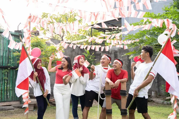 인도네시아 국기를 들고 대나무 막대기와 경주 장비가 달린 빨간색과 흰색 옷을 입은 친구들이 모여 있다 — 스톡 사진