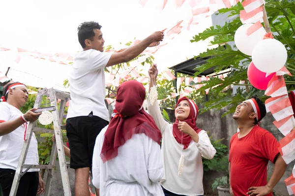 Pria berpakaian putih meletakkan tali untuk menggantung kerupuk dalam persiapan untuk Crecker Eating kontes — Stok Foto