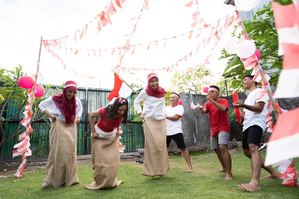 Pendukung laki-laki mengenakan atribut merah dan putih berteriak dalam mendukung para wanita karung pembalap — Stok Foto