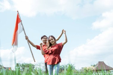 Endonezya bayrağı taşıyan Asyalı genç çift kırmızı bir özellik taşıyorlar.