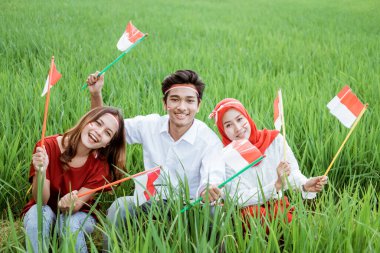 Üç Asya dostu gülümseme pirinç tarlalarının ortasında küçük bir bayrak taşıyor.