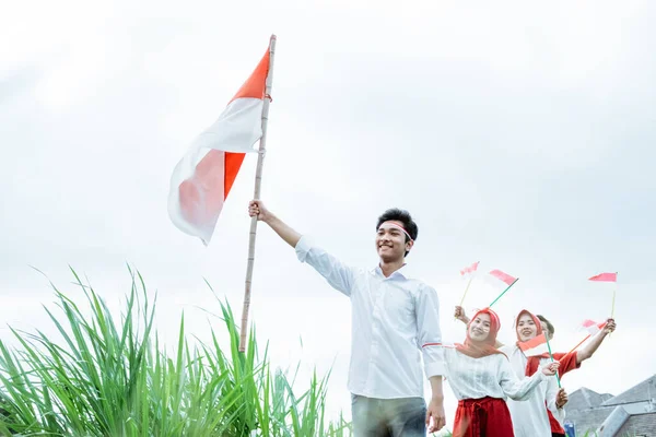 Un garçon en blanc portant un drapeau indonésien et ses amis derrière le suivent — Photo