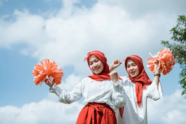 Dua gadis bercadar mengenakan atribut merah dan putih dibesarkan pompom — Stok Foto