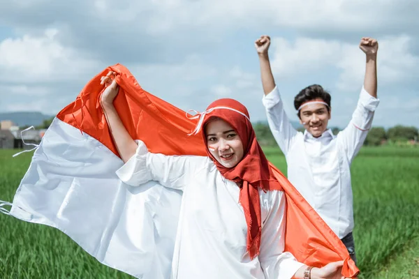 Hijab girl hold and raised the Indonesian flag and a boy raised hand — Stock Photo, Image