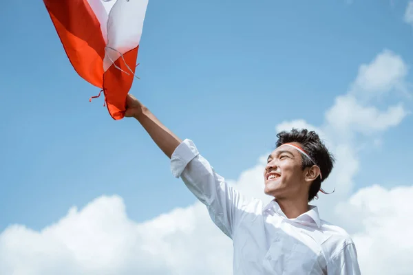 흰색 셔츠와 빨간색과 흰색의 특성을 입고 인도네시아 국기를 들고 있는 아시아 청소년들 — 스톡 사진