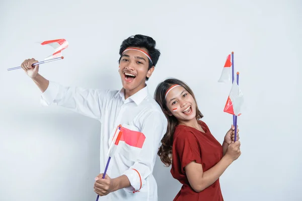 Pasangan muda memegang bendera Indonesia kecil dan mengenakan atribut merah dan putih — Stok Foto