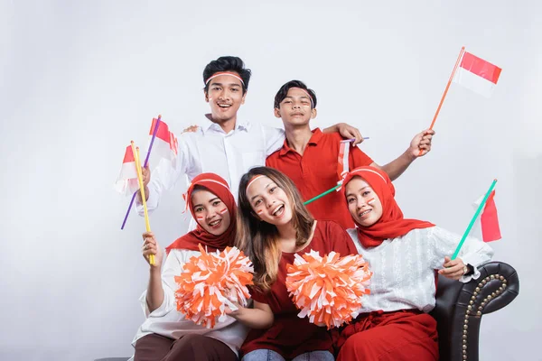Baráti társaság mosolyog kezében egy pompa és kis zászlók, míg visel az indonéz zászló — Stock Fotó