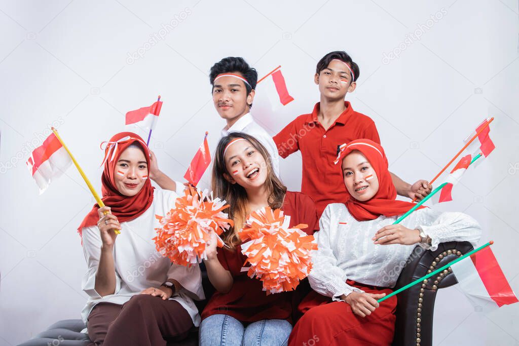 group of friends smiling holding a pompom and small flags while wearing the Indonesian flag