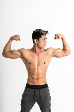 Genç adam kaslı pazılarını öne bakıyor.