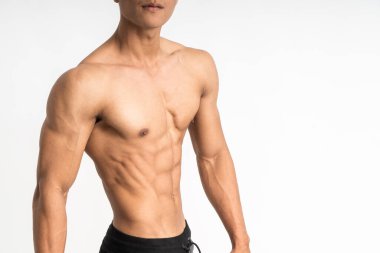Asyalı genç bir adamın kesilmiş görüntüsü kaslı bir karın bölgesini yana doğru gösteriyor.