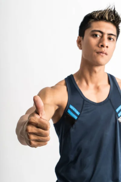 Cropped image of muscular young man wearing gym shirt stand facing to the side with thumbs up to the camera — Stock Photo, Image