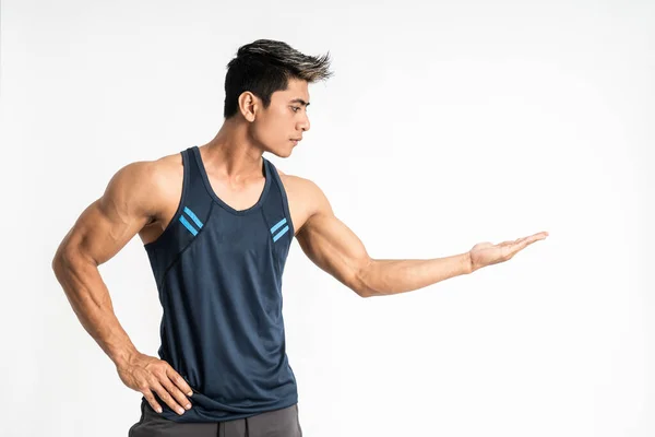 Musclé jeune homme asiatique en vêtements de sport se tient sur le côté avec quelque chose de présent sur sa main — Photo