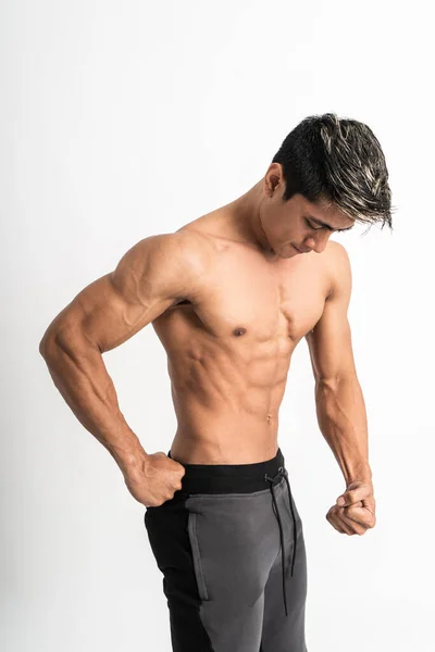 Man showing muscular abdomen and chest with one hand on waist — Stock Photo, Image