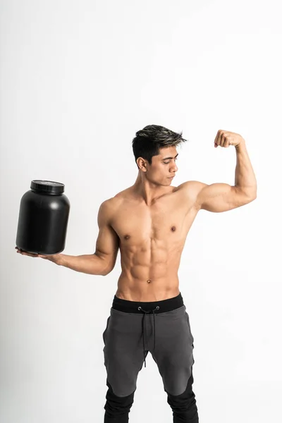 Man met gespierd lichaam dragen een zwarte fles met een hand, terwijl het tonen van gespierde biceps staan naar voren en kijk naar opzij — Stockfoto