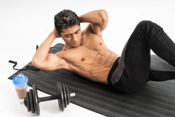 Muscle homme sans vêtements ne s'asseoir exercices avec un tapis à côté de la bouteille et haltère — Photo